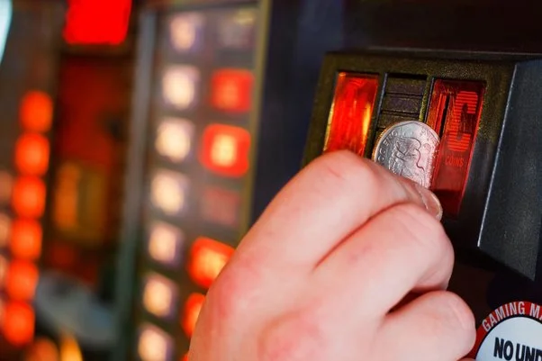 hand holding a penny puting it in slot machine